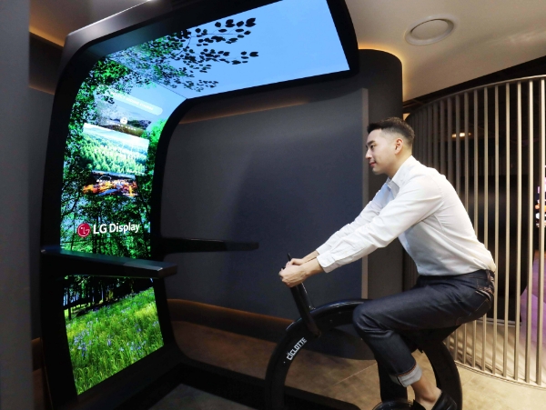 LG디스플레이 직원이 대형 OLED 스크린과 운동기구를 합친 콘셉트 제품 '버추얼 라이드'를 체험하고 있다. /사진=LG디스플레이