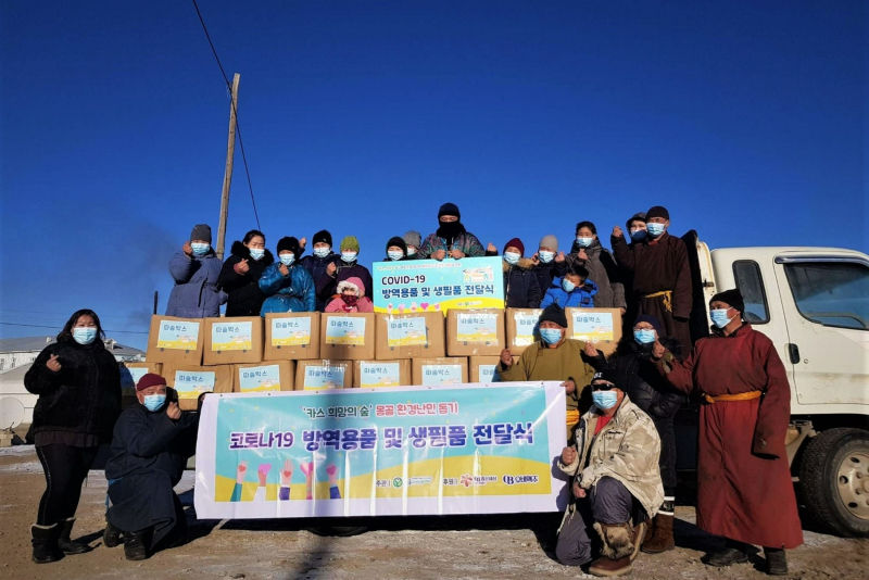 몽골 카스 희망의 숲 인근 하늘마을 주민들이 푸른아시아의 현지 활동가와 따숨박스 전달식에 참석해 기념사진을 찍고 있다./사진=오비맥주
